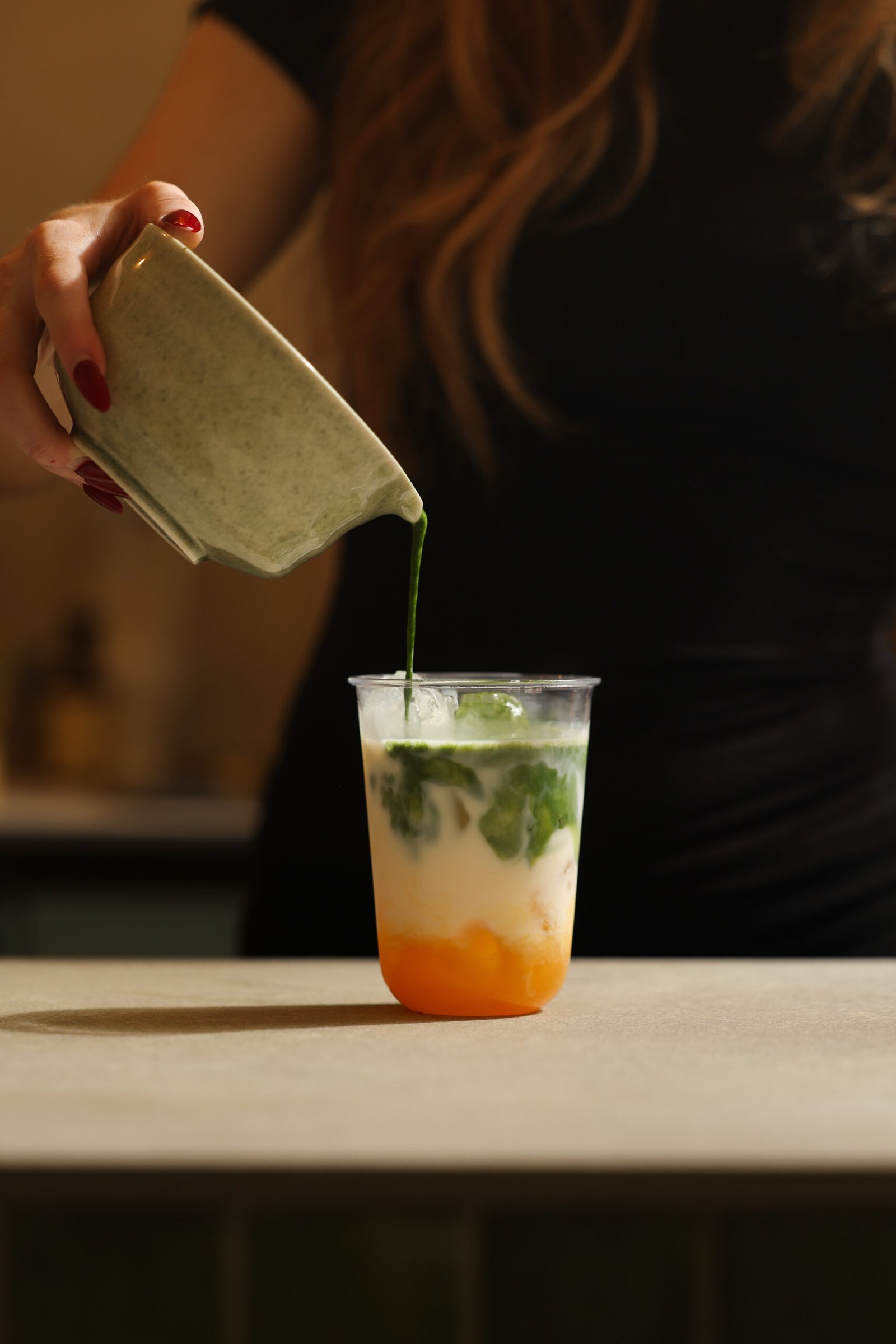 Iced matcha being poured over milk at Forma